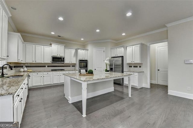 kitchen featuring sink, stainless steel appliances, a center island, and light stone countertops