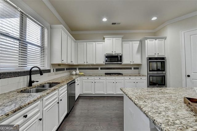 kitchen featuring sink, appliances with stainless steel finishes, backsplash, ornamental molding, and white cabinets