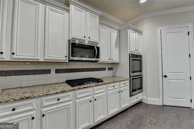 kitchen with stainless steel appliances, light stone countertops, white cabinets, and backsplash