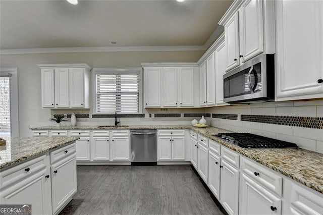 kitchen featuring sink, ornamental molding, appliances with stainless steel finishes, a healthy amount of sunlight, and white cabinets