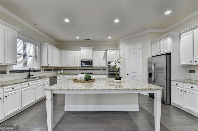 kitchen with light stone countertops, a center island, appliances with stainless steel finishes, and sink