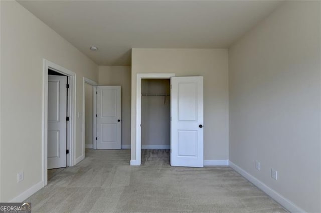 unfurnished bedroom with light colored carpet and a closet