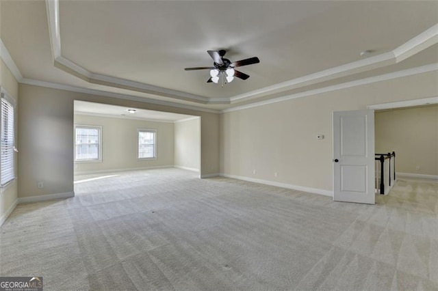 carpeted empty room featuring crown molding, ceiling fan, and a tray ceiling