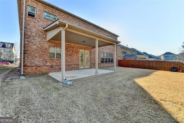 back of property with a lawn and a patio