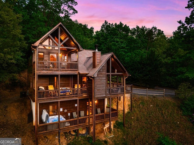 back house at dusk featuring a balcony