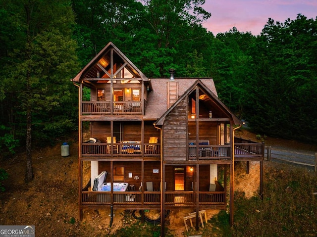 back house at dusk featuring a balcony