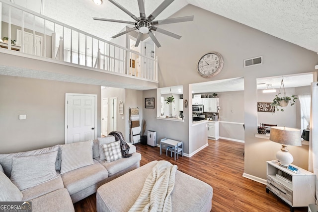 living room featuring ceiling fan, high vaulted ceiling, a textured ceiling, and dark hardwood / wood-style flooring