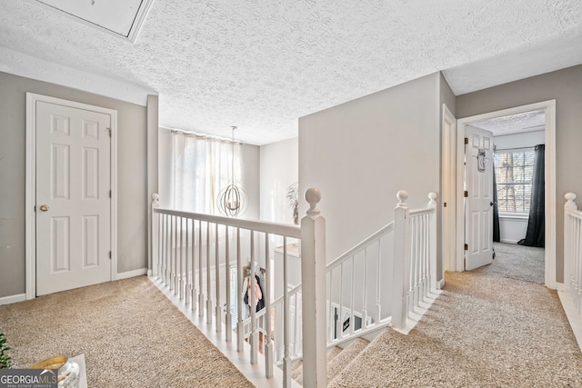 corridor with light carpet and a textured ceiling