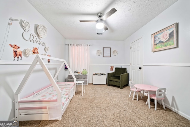 carpeted bedroom with ceiling fan and a textured ceiling