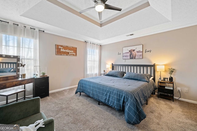 bedroom featuring crown molding, a tray ceiling, a textured ceiling, and carpet