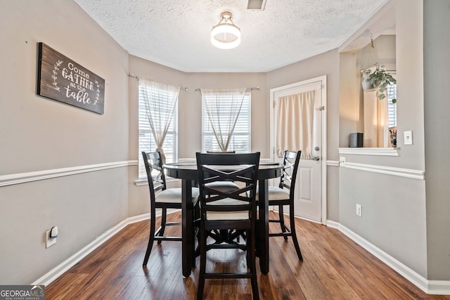 dining room featuring dark hardwood / wood-style flooring and a textured ceiling