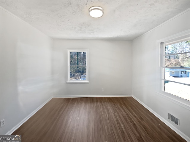 spare room featuring dark hardwood / wood-style floors and a textured ceiling