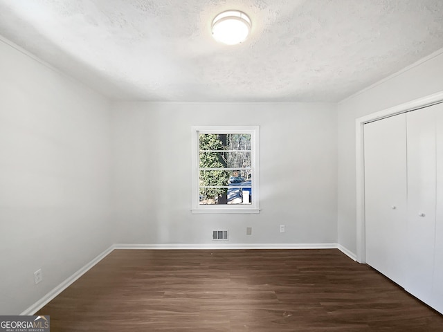 unfurnished bedroom with dark wood-type flooring, a closet, and a textured ceiling