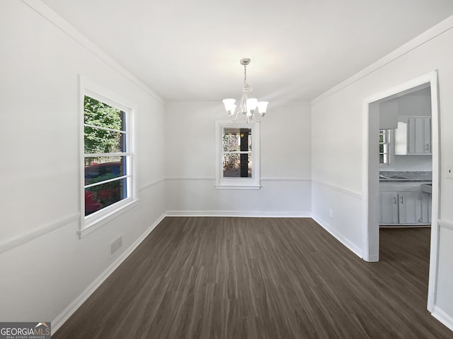 unfurnished dining area featuring ornamental molding, dark wood-type flooring, and a chandelier