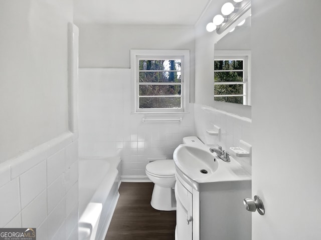 bathroom with vanity, a bathing tub, tile walls, and toilet