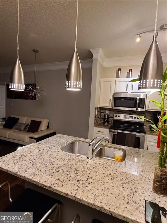 kitchen with light stone counters, stainless steel appliances, a kitchen bar, and white cabinets