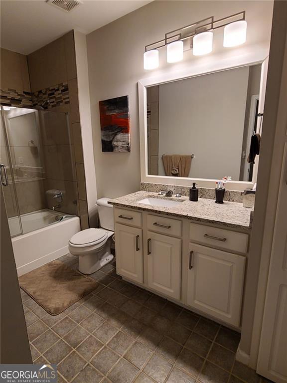 full bathroom with vanity, bath / shower combo with glass door, and toilet