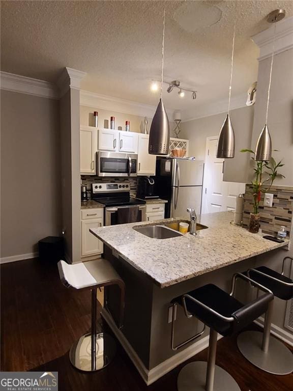 kitchen featuring appliances with stainless steel finishes, a kitchen breakfast bar, hanging light fixtures, and white cabinets