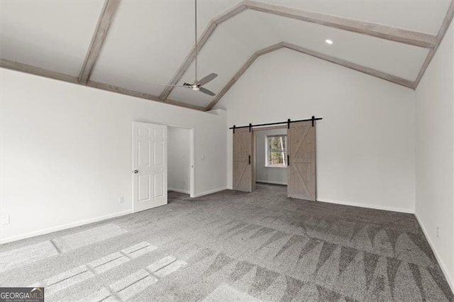 carpeted empty room featuring a barn door, high vaulted ceiling, and ceiling fan