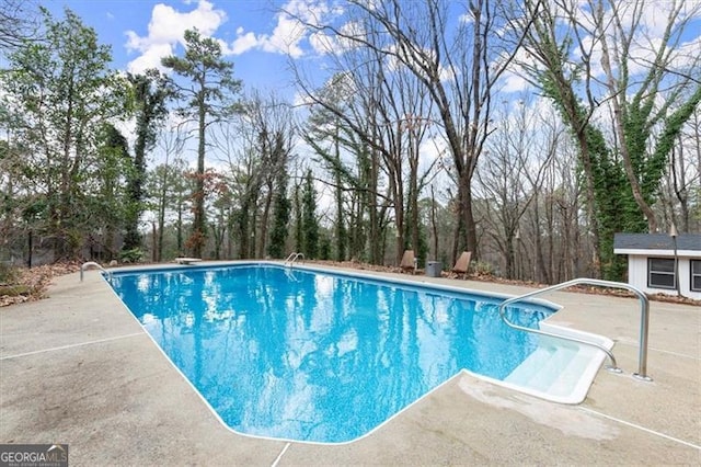 view of pool featuring a diving board, an outbuilding, and a patio area