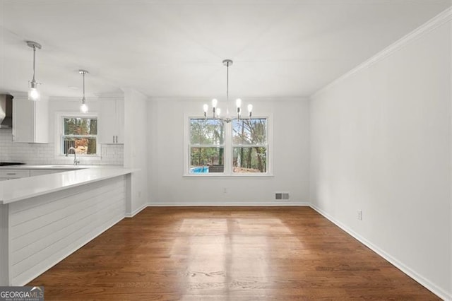 unfurnished dining area with crown molding, sink, a chandelier, and dark hardwood / wood-style flooring