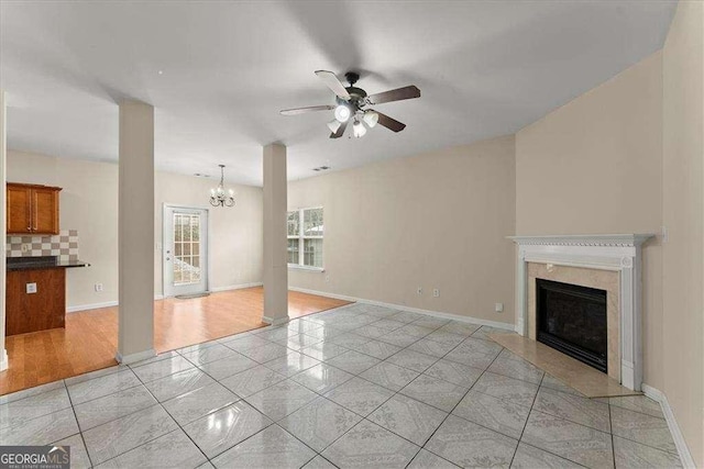 unfurnished living room featuring a fireplace and ceiling fan with notable chandelier