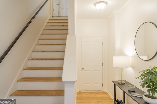 staircase with crown molding and wood-type flooring