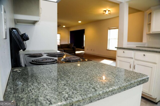 kitchen with light stone countertops, white cabinets, and kitchen peninsula