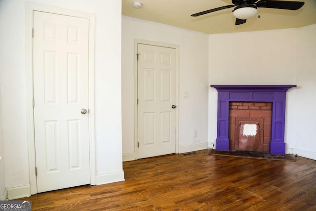 interior space featuring a brick fireplace, dark hardwood / wood-style floors, and ceiling fan