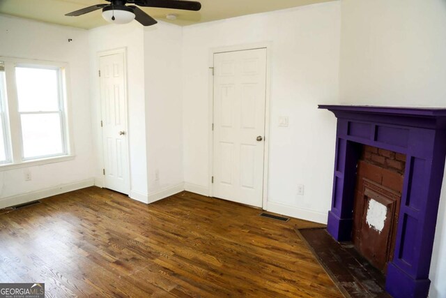 unfurnished living room featuring ceiling fan and dark hardwood / wood-style flooring