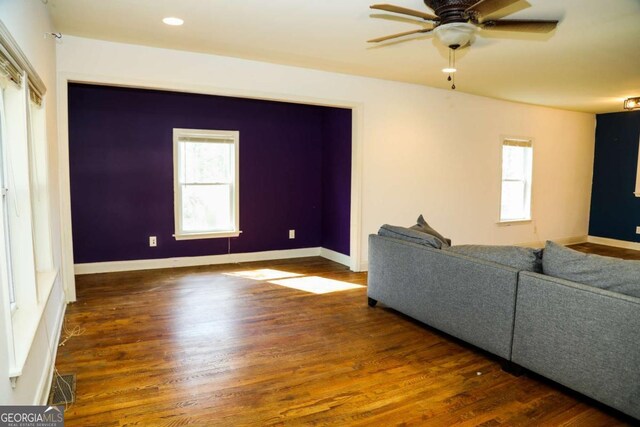 unfurnished living room featuring dark wood-type flooring, a wealth of natural light, and ceiling fan