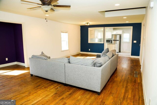 living room with dark wood-type flooring and ceiling fan