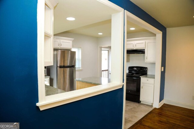 kitchen with white cabinetry, black electric range oven, dark wood-type flooring, and stainless steel fridge