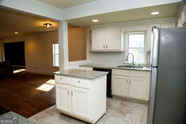 kitchen with sink, stainless steel fridge, dishwasher, white cabinetry, and a kitchen island