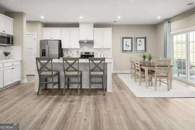 kitchen featuring decorative backsplash, appliances with stainless steel finishes, a kitchen island, and white cabinets