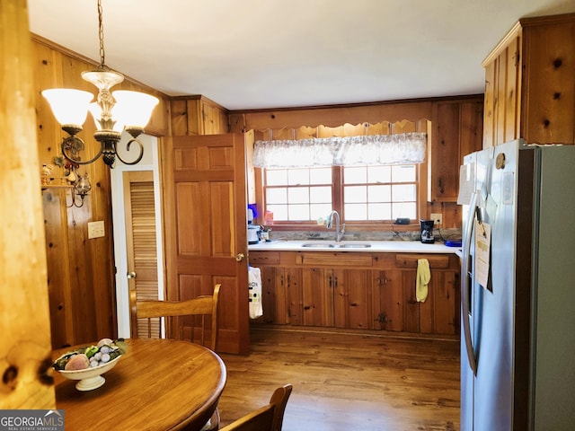 kitchen featuring stainless steel refrigerator, decorative light fixtures, sink, a notable chandelier, and light hardwood / wood-style flooring