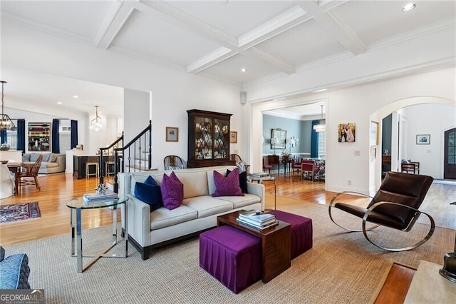 living room featuring an inviting chandelier, light hardwood / wood-style flooring, and coffered ceiling