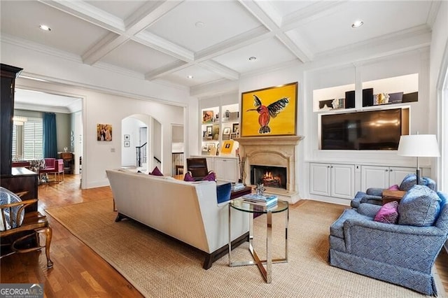 living room featuring coffered ceiling, light hardwood / wood-style flooring, ornamental molding, and beamed ceiling