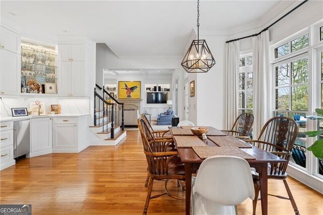 dining space with crown molding, a chandelier, and light hardwood / wood-style flooring