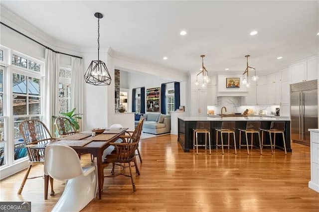 dining area with ornamental molding and light hardwood / wood-style floors