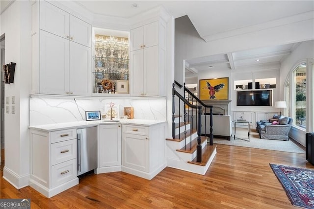 bar featuring beam ceiling, light hardwood / wood-style flooring, fridge, and white cabinets