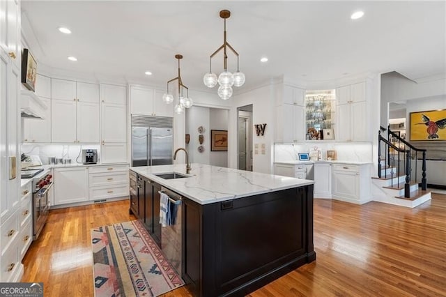 kitchen featuring pendant lighting, sink, a kitchen island with sink, white cabinetry, and high quality appliances