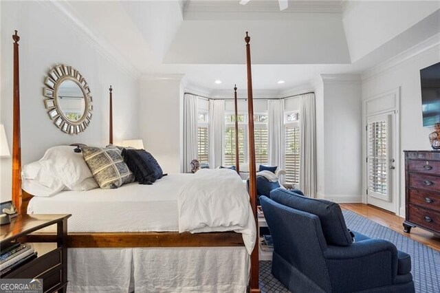 bedroom with hardwood / wood-style flooring, ornamental molding, access to exterior, and a tray ceiling