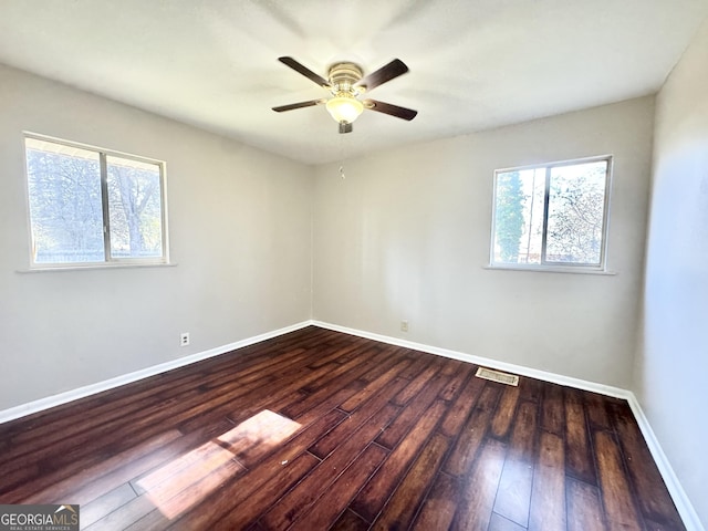 empty room featuring plenty of natural light, dark wood-type flooring, and ceiling fan