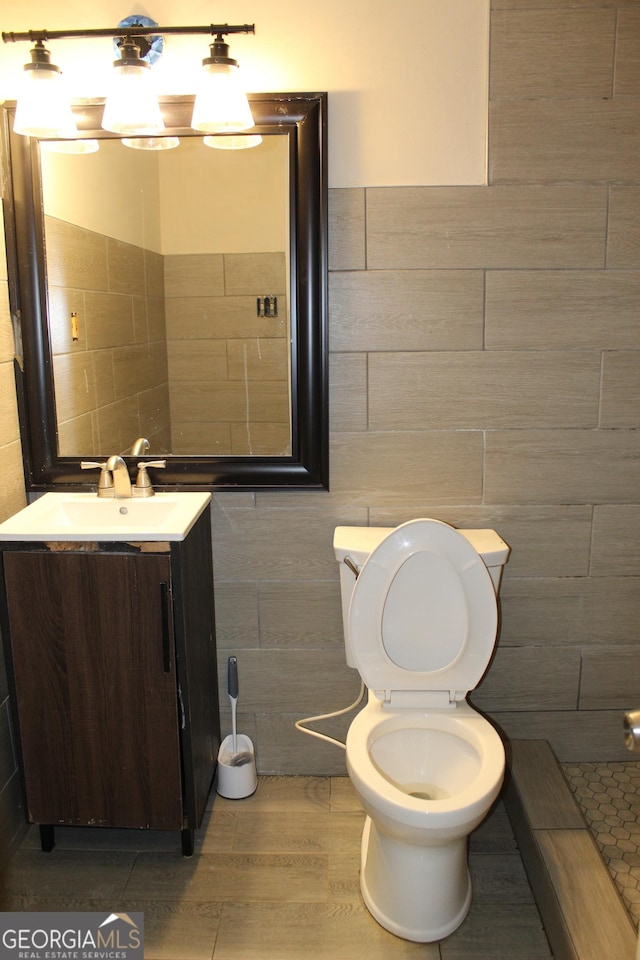 bathroom with vanity, tile walls, and toilet