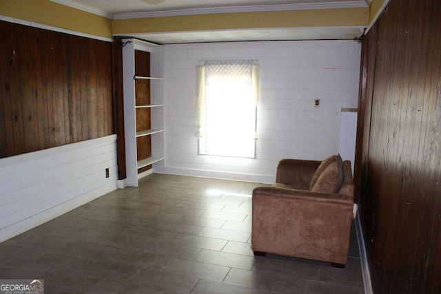 living area with ornamental molding and wood walls