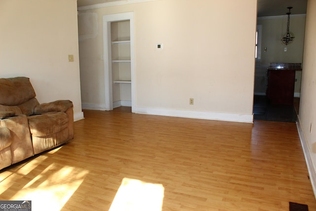 living room with ornamental molding and light hardwood / wood-style flooring