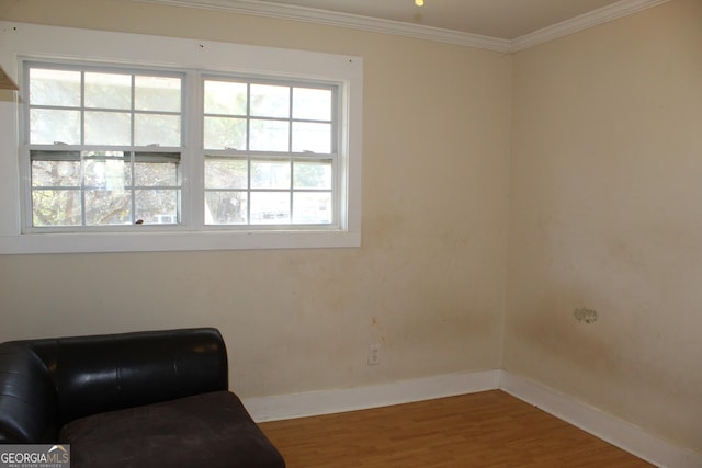 living area with hardwood / wood-style flooring, a healthy amount of sunlight, and ornamental molding