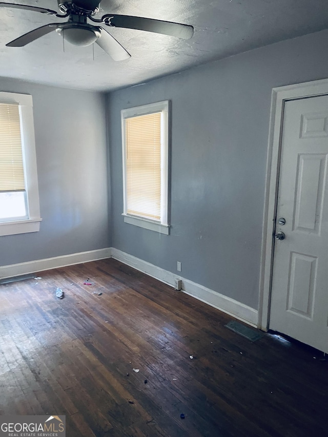 unfurnished room with ceiling fan and dark hardwood / wood-style floors