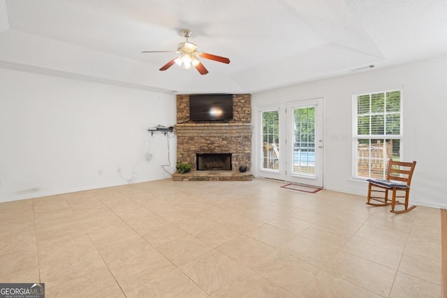 unfurnished living room featuring a raised ceiling, ceiling fan, light tile patterned flooring, and a fireplace